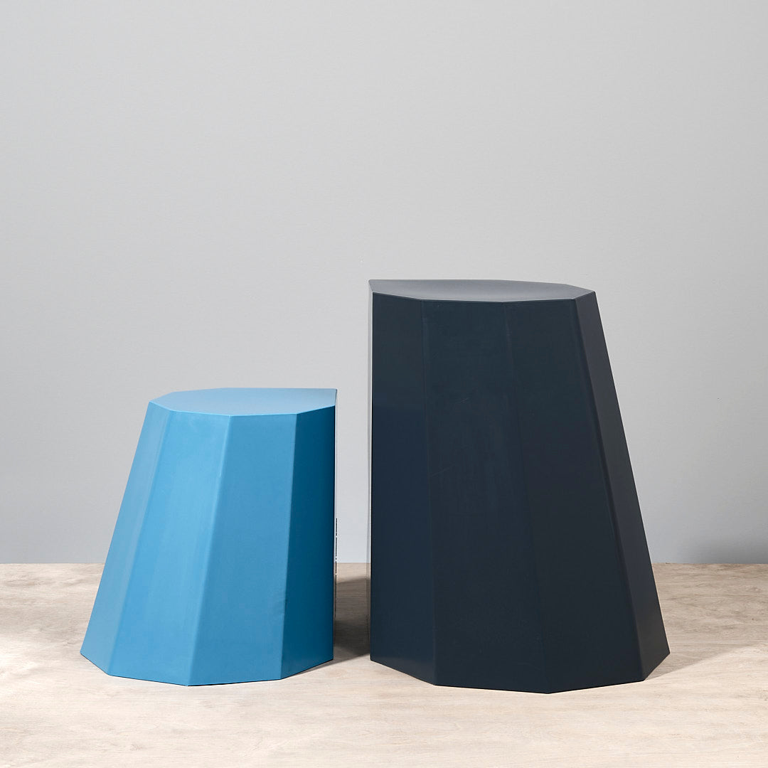 A pair of Arnold Circus Stool - Boat Blue stools on a wooden surface. Brand: Martino Gamper