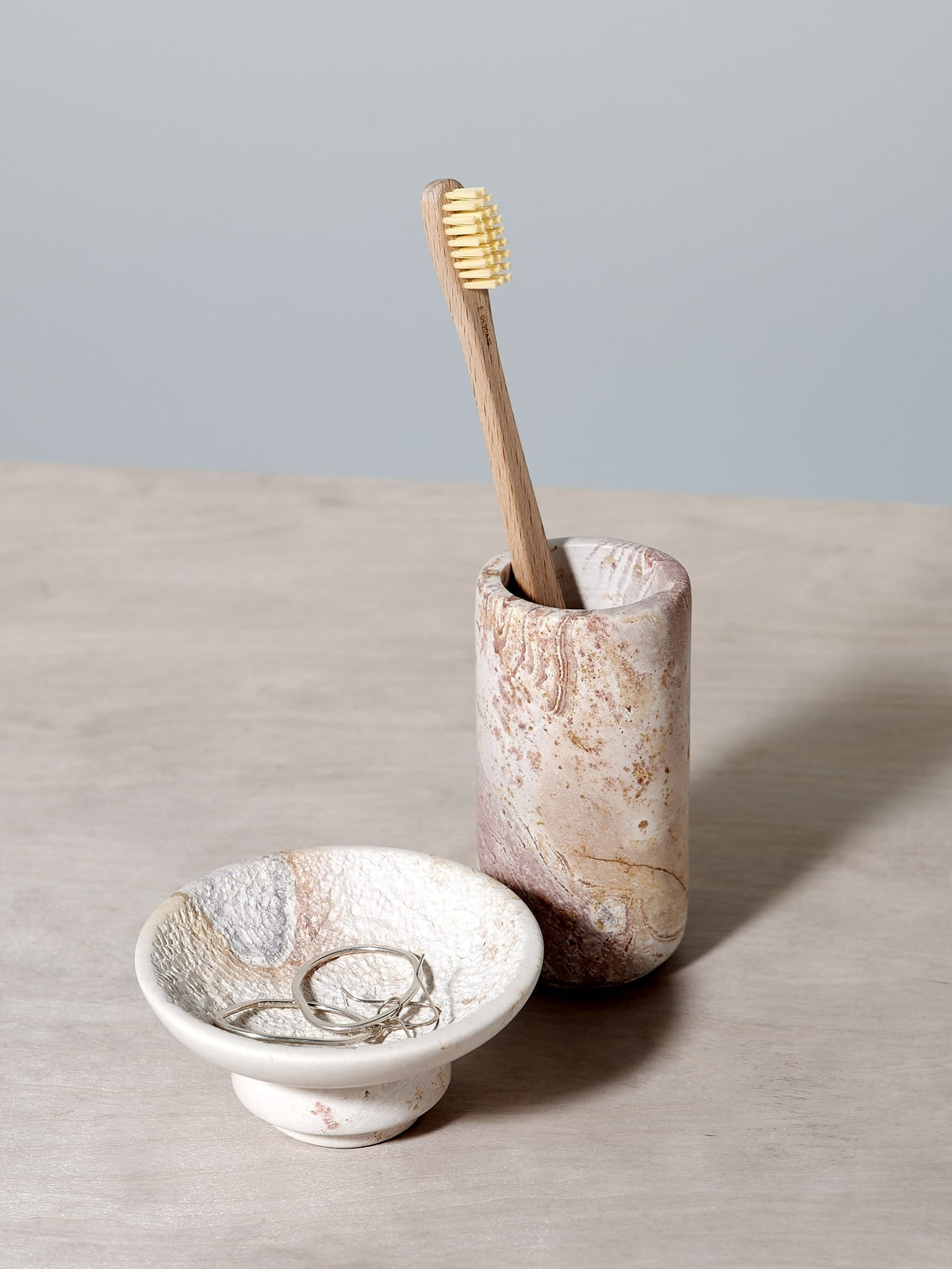 An Amina Bowl Set Small – Pink and toothbrush holder on a table.