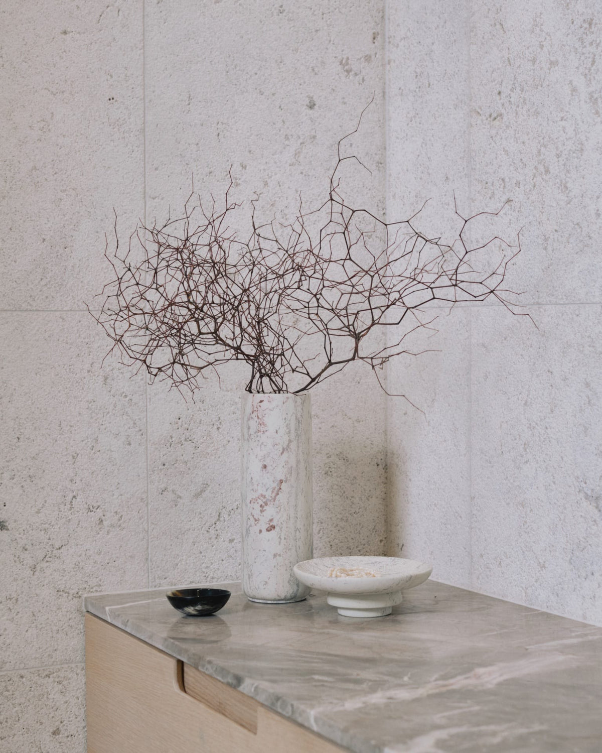 An Amina Bowl Set Tall - Pink by Asili with a branch on top of a marble counter.