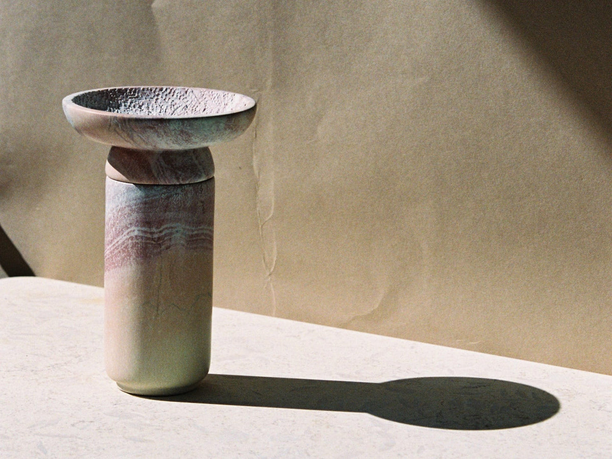 An &quot;Amina Bowl Set Small – Pink&quot; by Asili sitting on a table next to a wall.