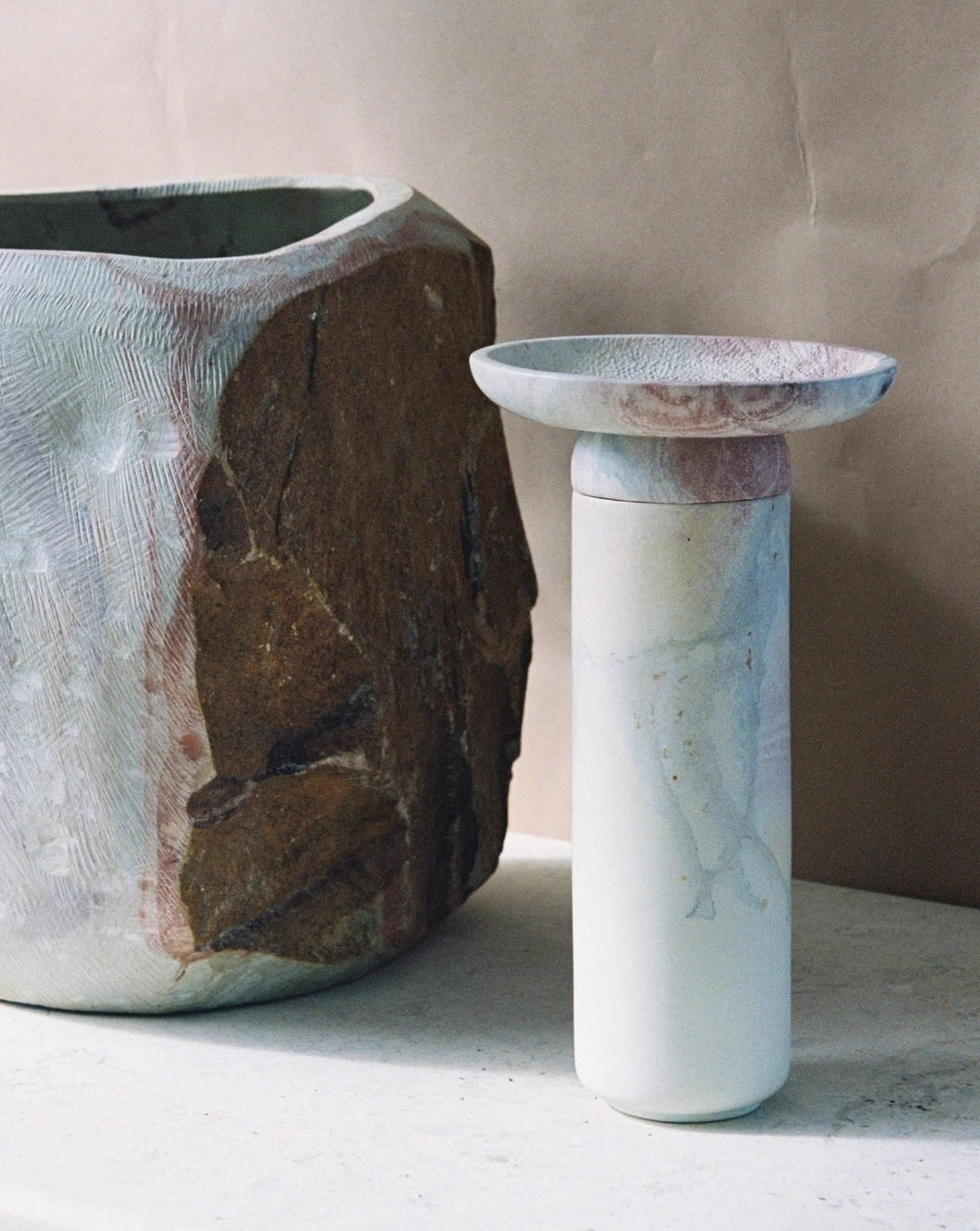 An Amina Bowl Set Tall – Pink by Asili and a rock next to each other.