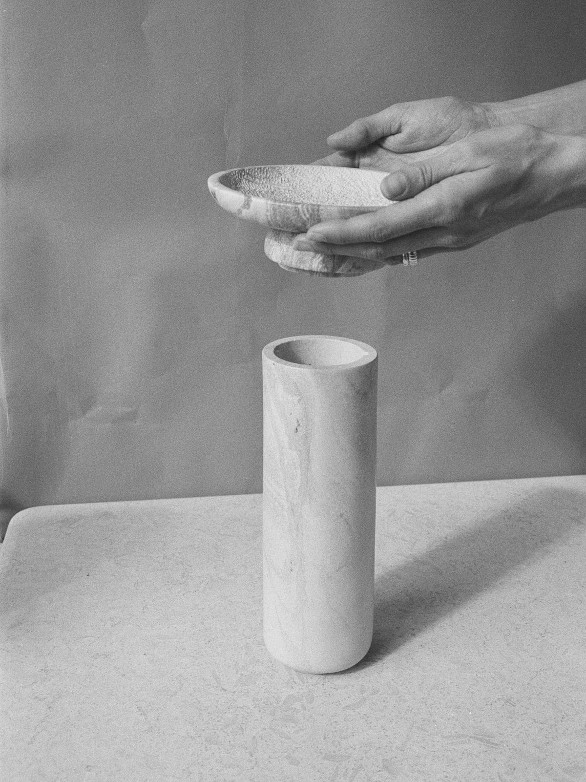 A black and white photo of a person putting an Asili Amina Bowl Set Tall – Pink into a vase.