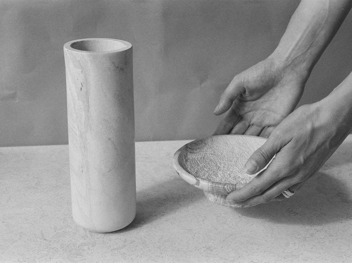 A black and white photo of a hand holding an Amina Bowl Set Tall – Pink by Asili.