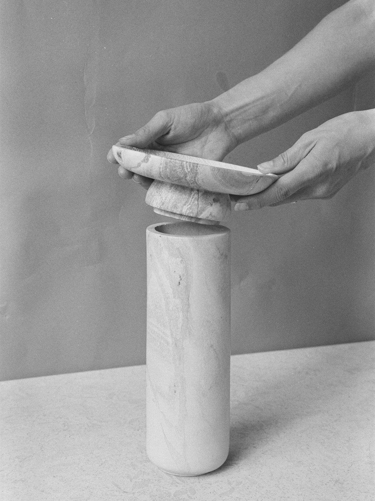 A black and white photo of a person putting an Asili Amina Bowl Set Tall - Pink into a vase.