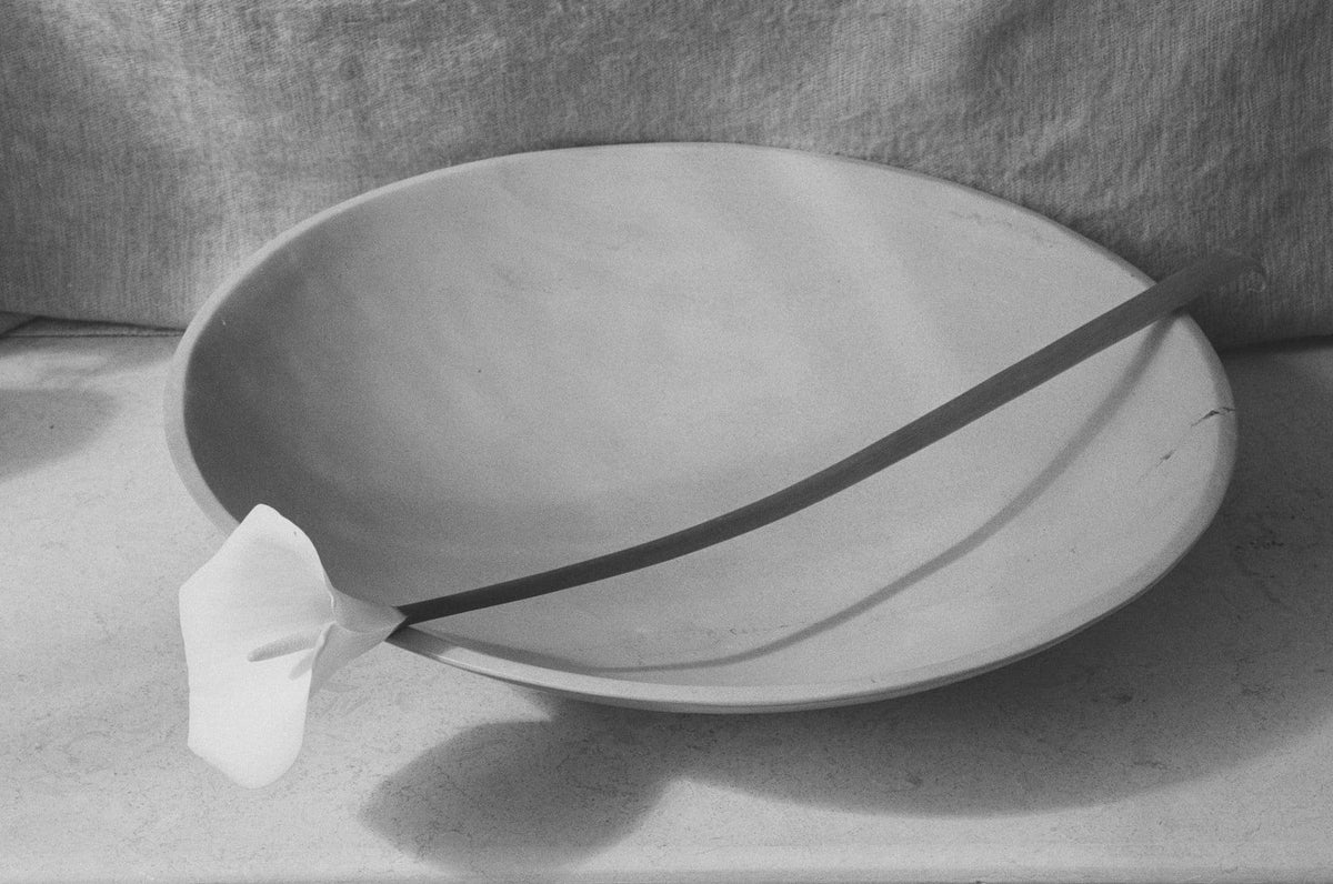 A black and white photo of a large dish - Malachite with a stick in it by Asili.