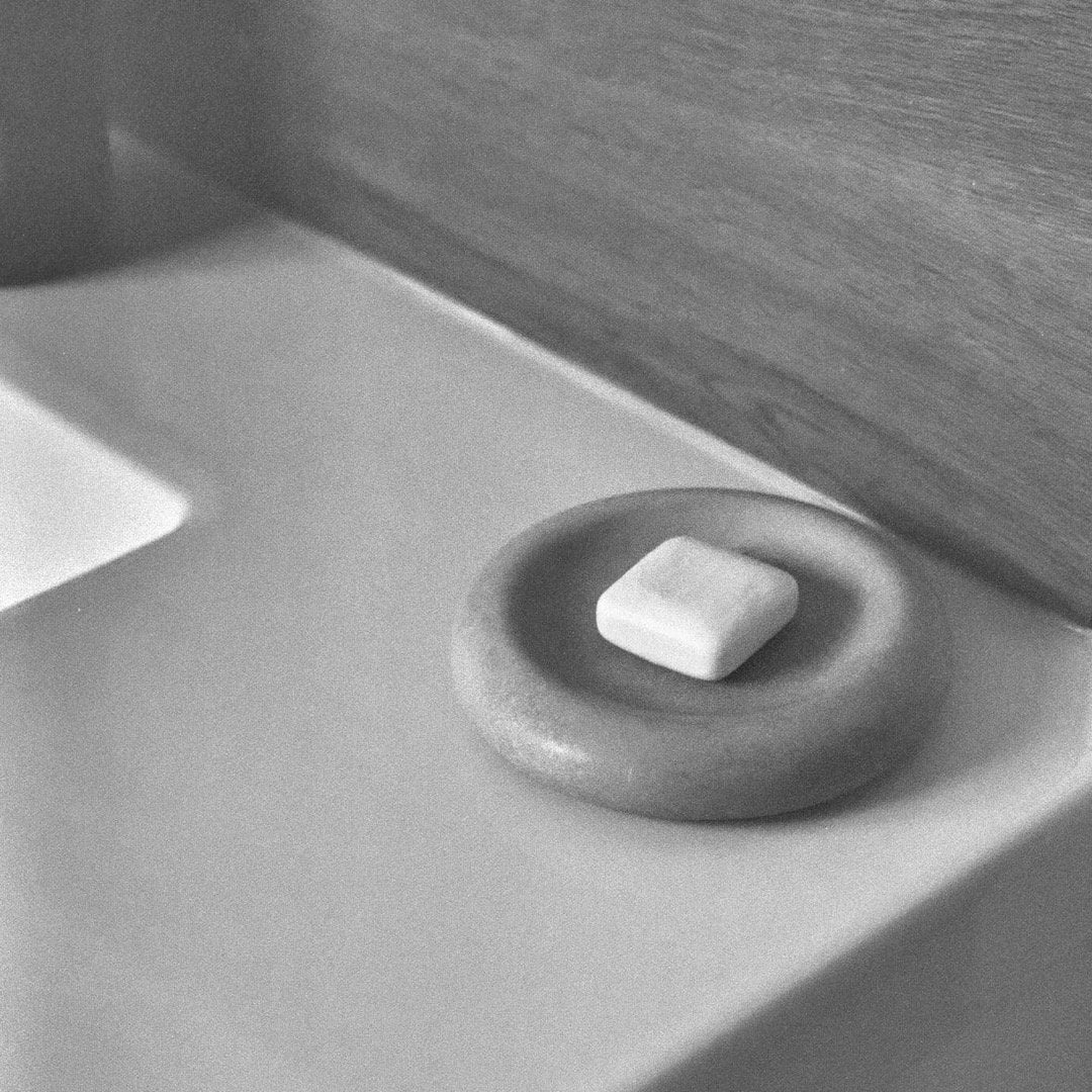Black and white photo of an Asili Stacker Round Tray – White soap dispenser on a sink.