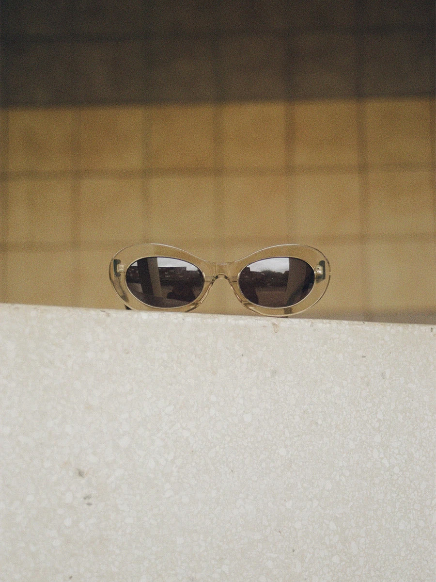 A pair of auór Paloma Sunglasses – Tea sitting on top of a wall.