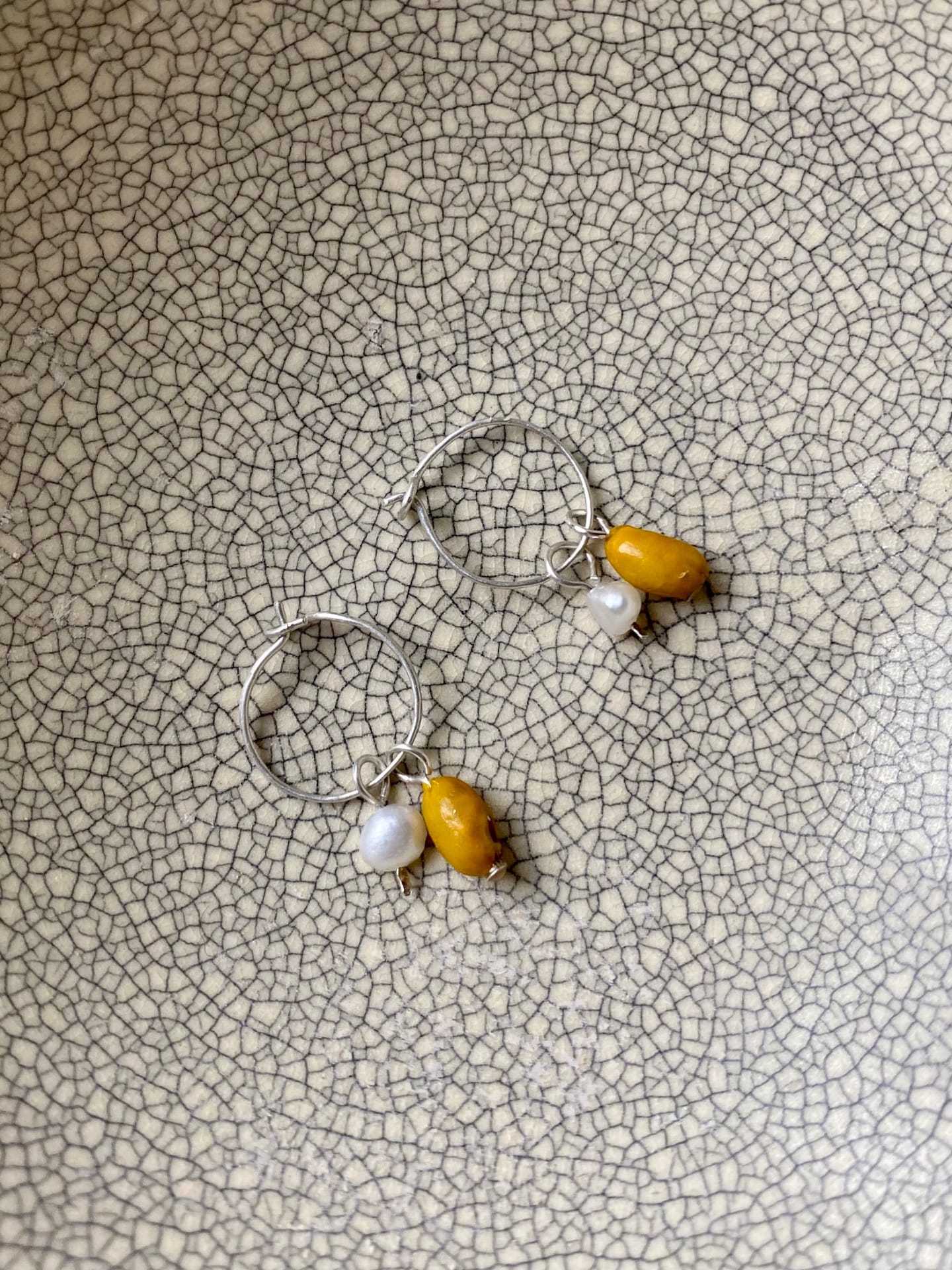 A pair of Kōwhai Sleepers hoop earrings by Avara Studio on a plate.