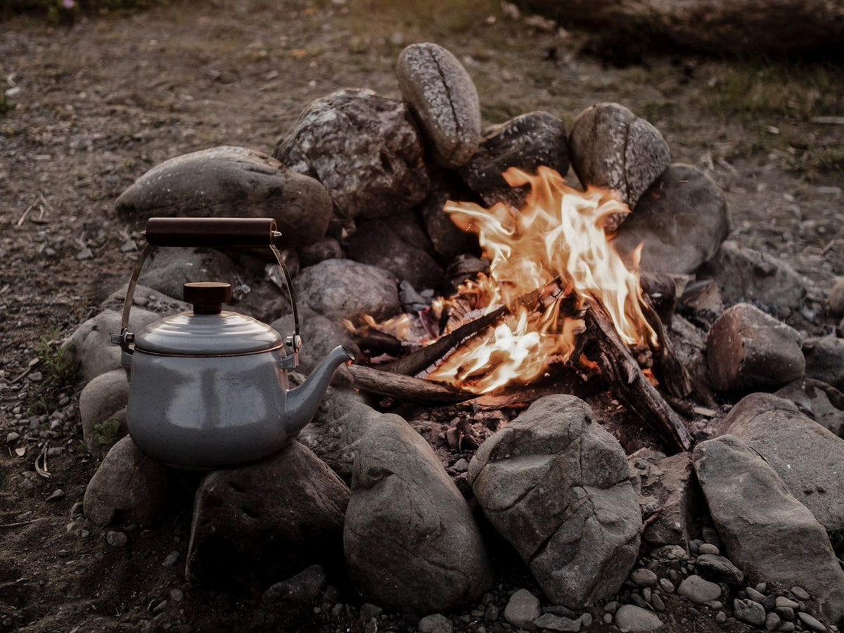 A campfire with a Barebones Enamel Teapot – Slate Grey sitting next to it.