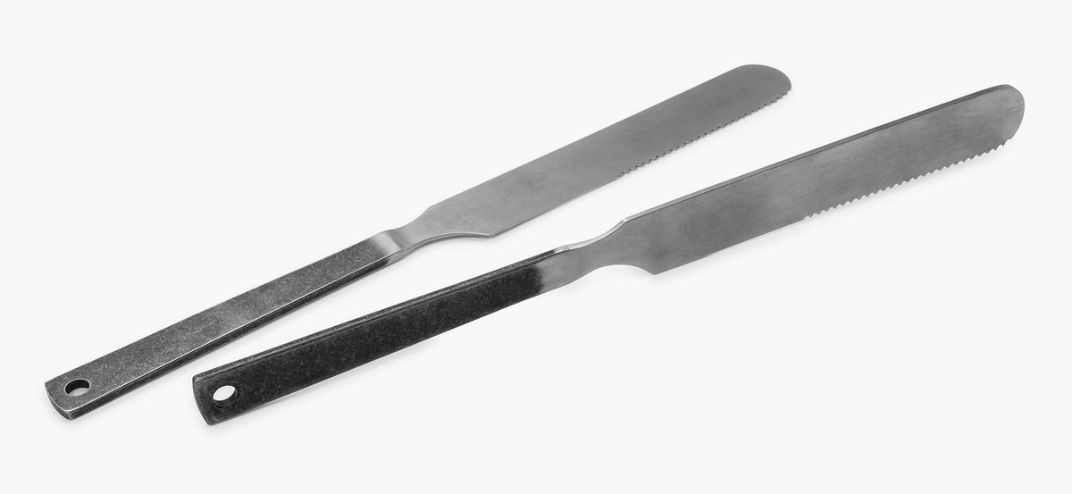 Two Barebones minimalist stainless steel spatulas with serrated edges are placed side by side on a white background.