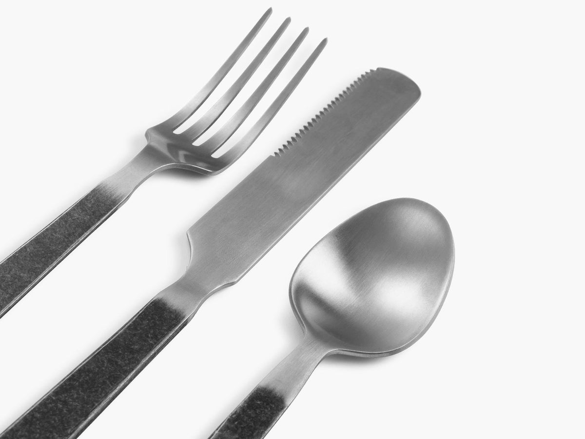 The Barebones Flatware Cutlery set includes minimalist stainless steel forks, knives, and spoons showcased on a white background.
