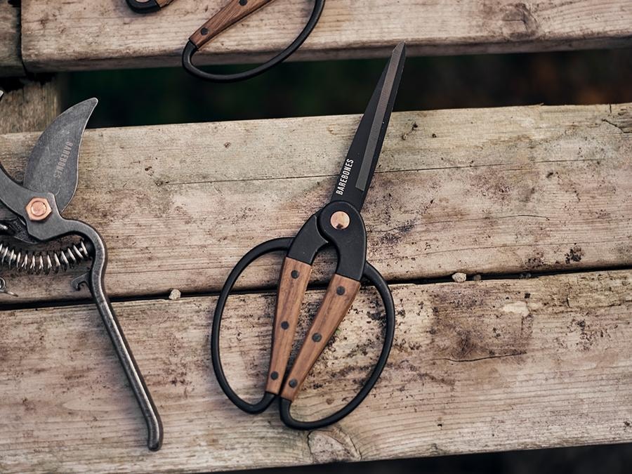 Three pairs of Barebones Walnut Garden Scissors – Large on a wooden bench.