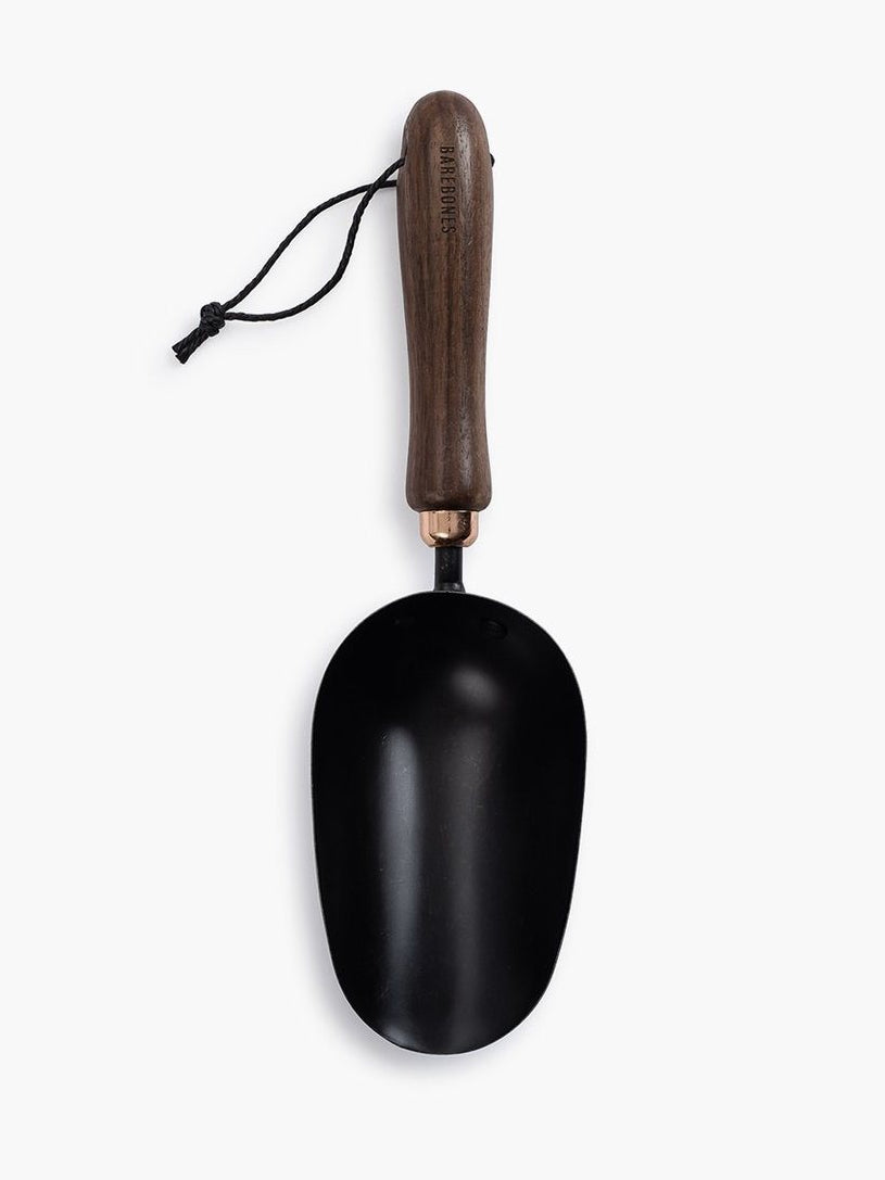 A black Garden Scoop with a wooden handle on a white background by Barebones.