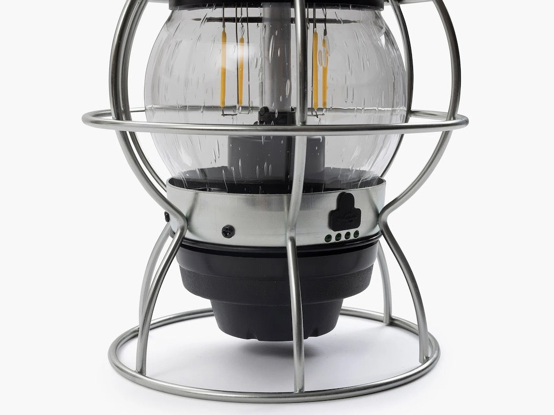 A Barebones Railroad Lantern – Olive Drab in a metal cage on a white background.