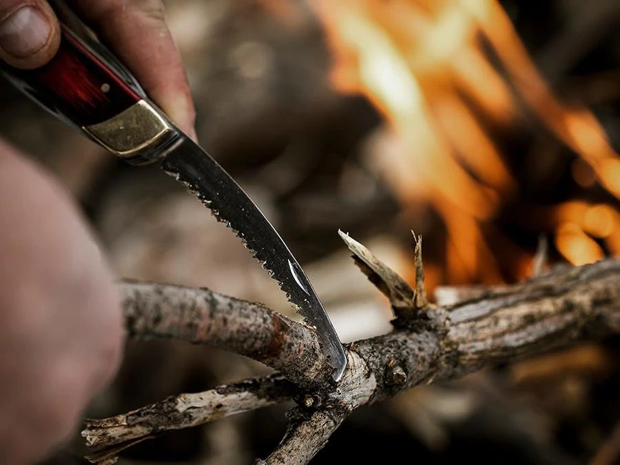 A person is holding a Barebones Multi-Tool Pocket Knife over a fire.