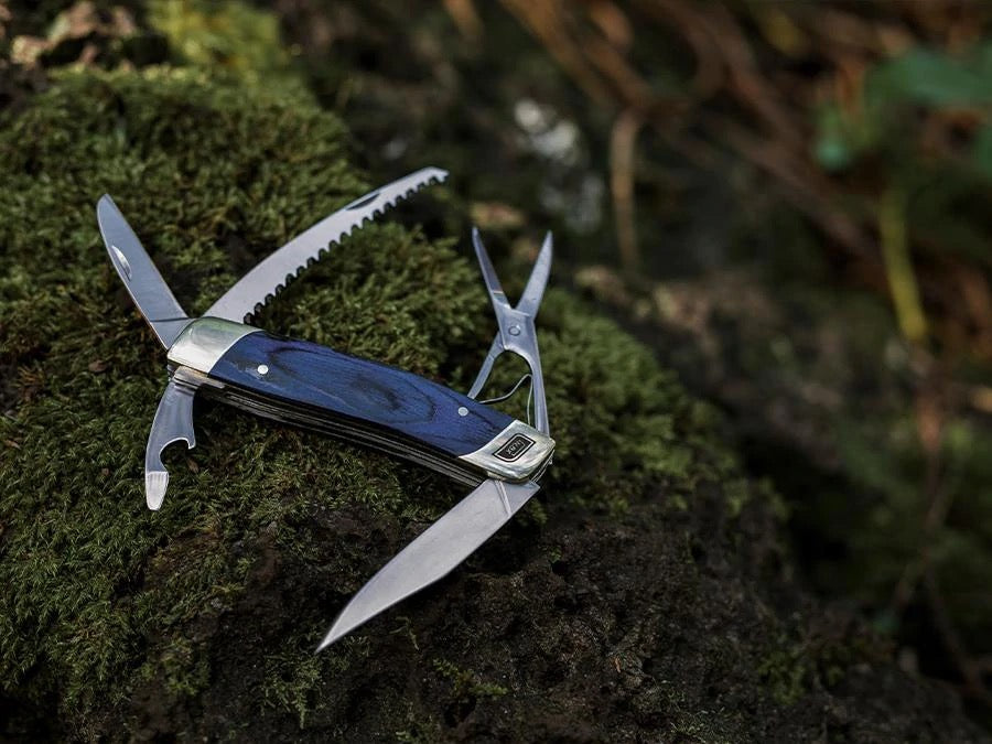 A Barebones Multi-Tool Pocket Knife is sitting on top of some moss.