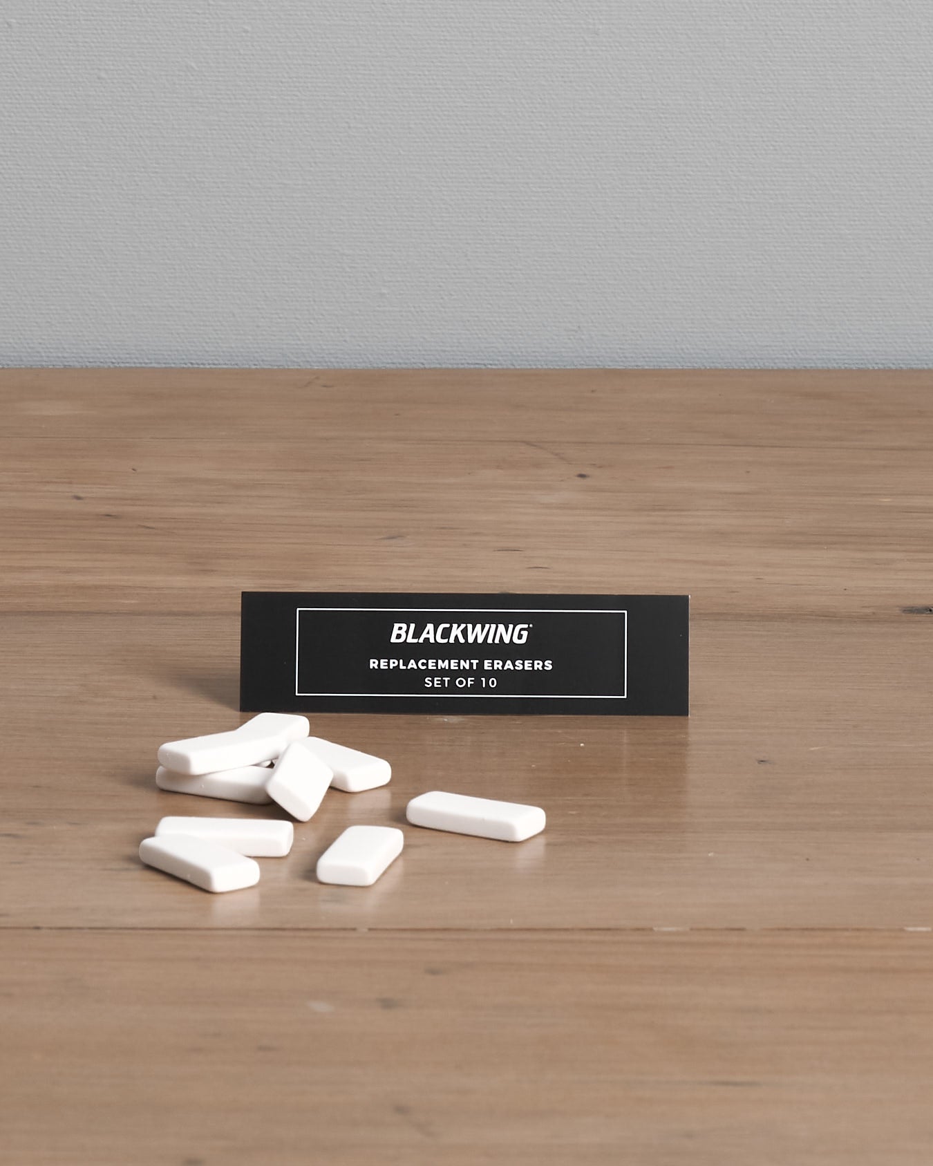 A pack of Palomino Blackwing Replacement Eraser 10pk – White ⋄ Black ⋄ Pink, designed with a dust-free design, displayed on a wooden surface.