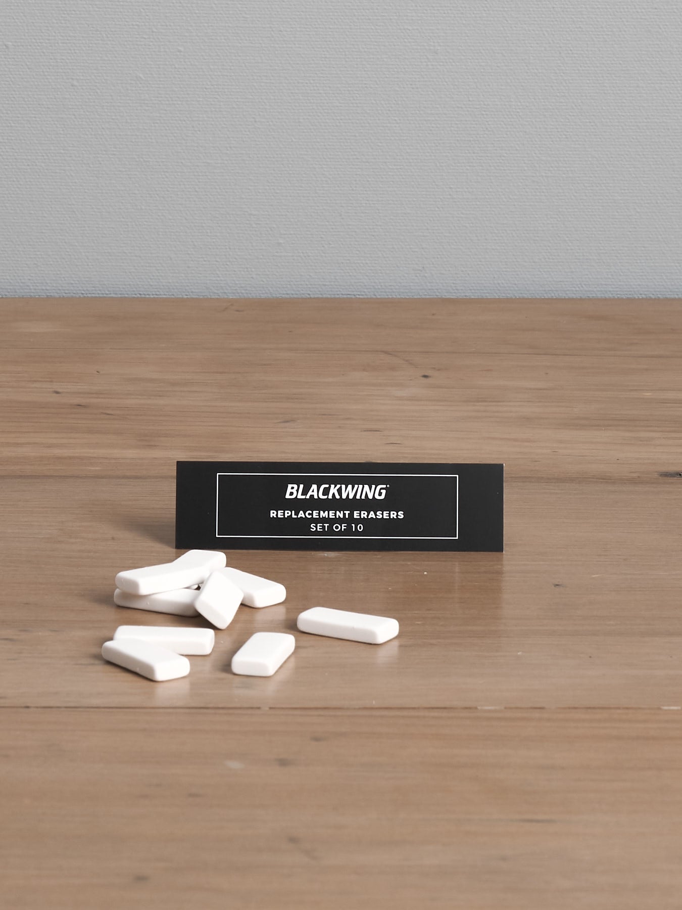 A pack of Palomino Blackwing Replacement Eraser 10pk – White ⋄ Black ⋄ Pink, designed with a dust-free design, displayed on a wooden surface.