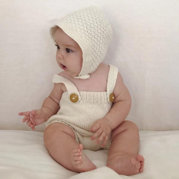 A baby wearing a white Hand Knitted Baby Bonnet - Natural romper and hat from Weebits.