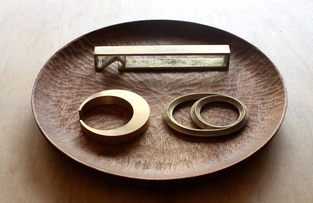 Three Eclipse Bottle Openers – Solid Brass by Futagami on a wooden plate.