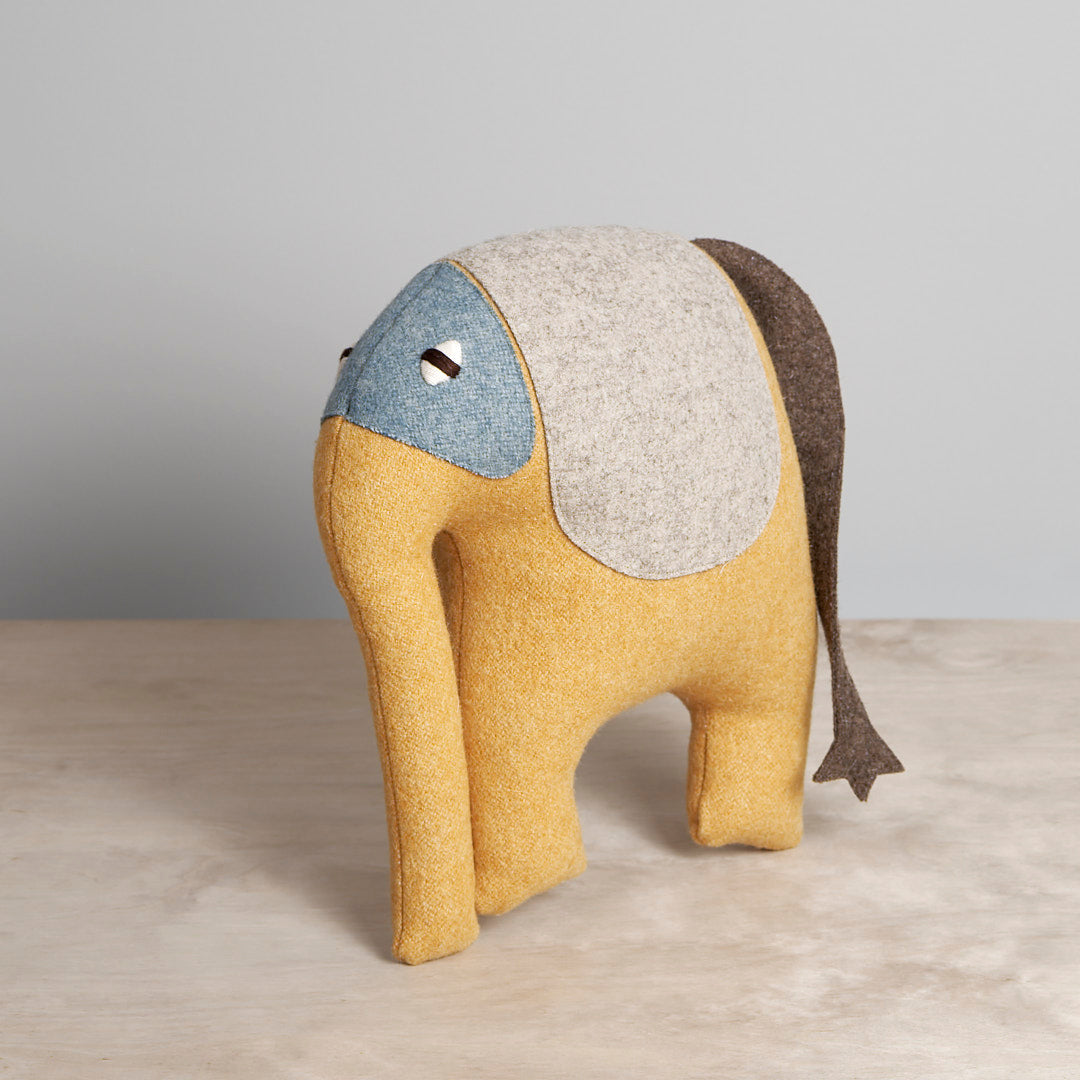 A DEEP, the Indian Elephant stuffed toy is sitting on a table.
