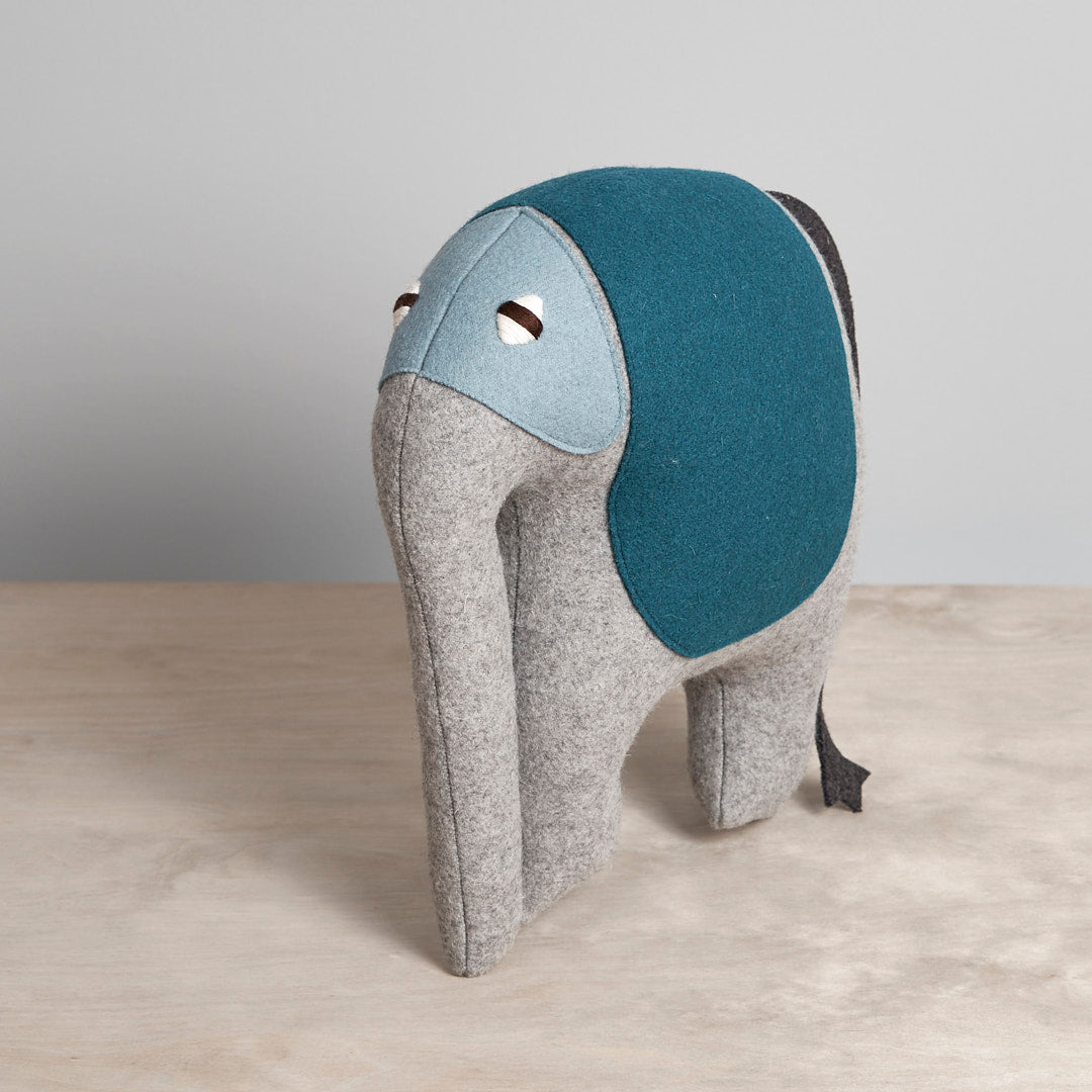 An IAN, the African Bush Elephant stuffed animal with a blue and grey jacket, from the Carapau brand.
