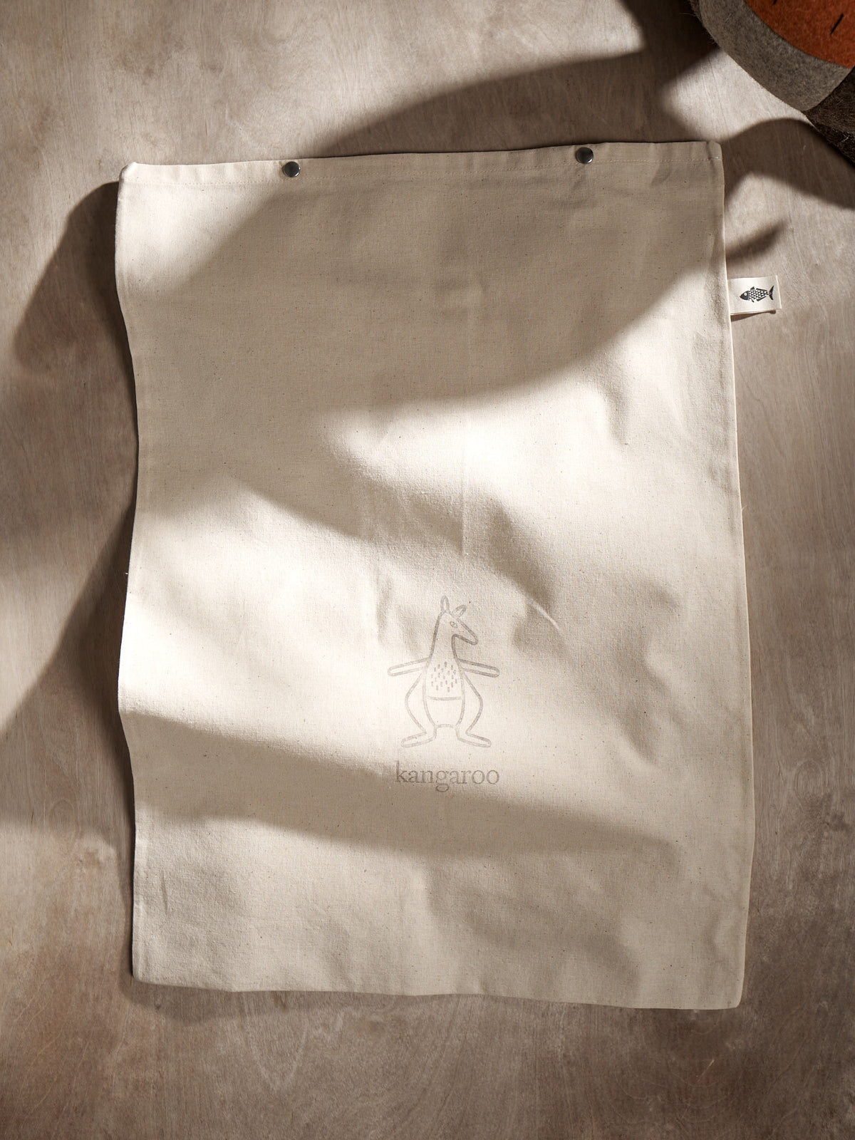 A JOE, the Kangaroo tote bag on a table next to a coffee cup. (Brand Name: Carapau)