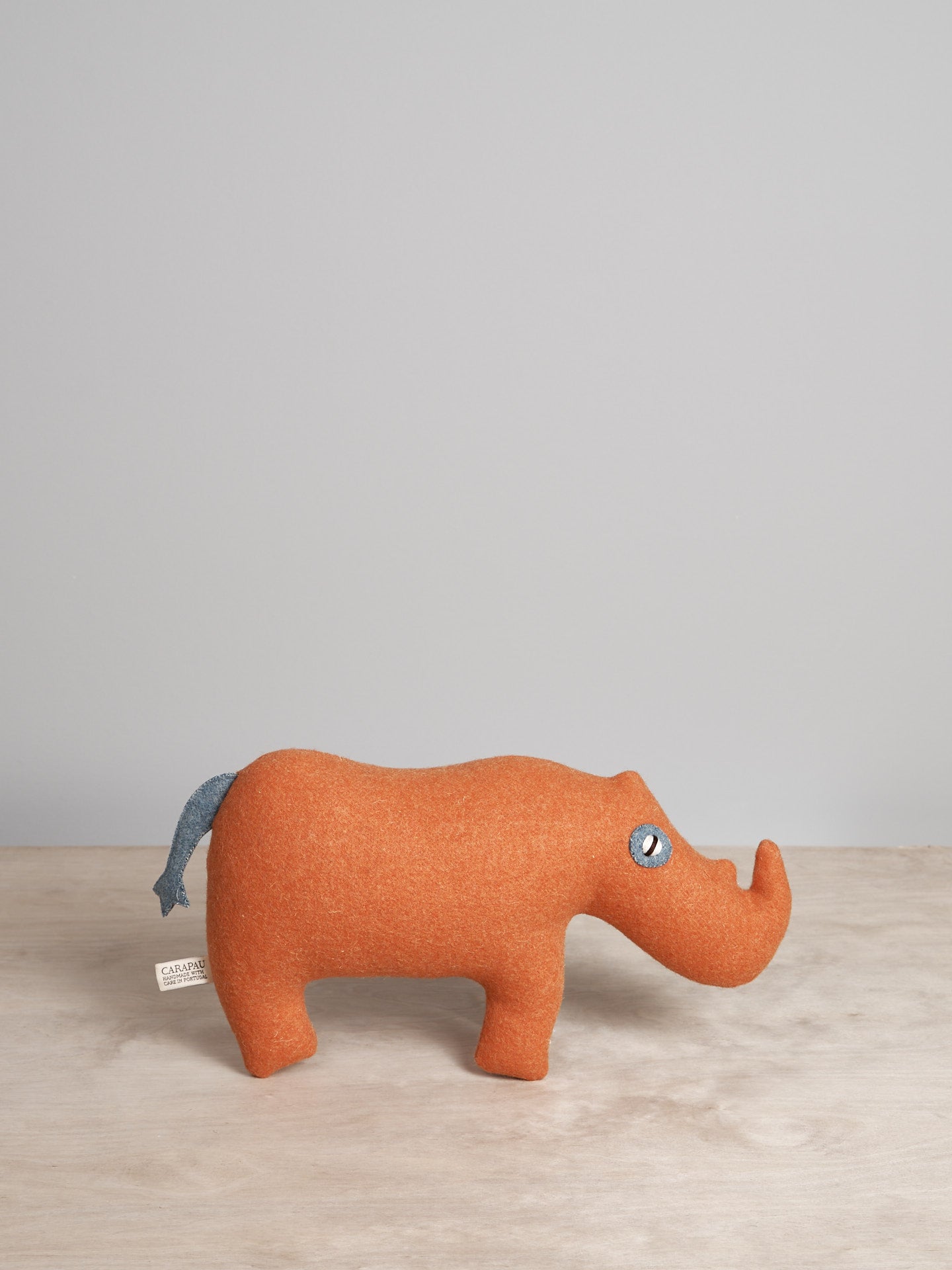 A JONAH, the Sumatran Rhino toy hippo is sitting on top of a Carapau wooden table.