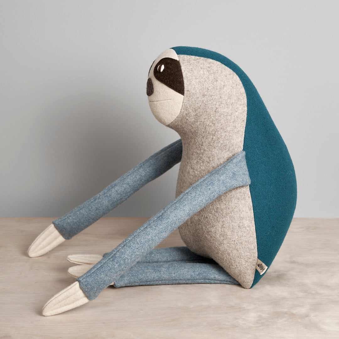 A NED, the Brown-Throated Sloth stuffed animal sitting on a table from Carapau.
