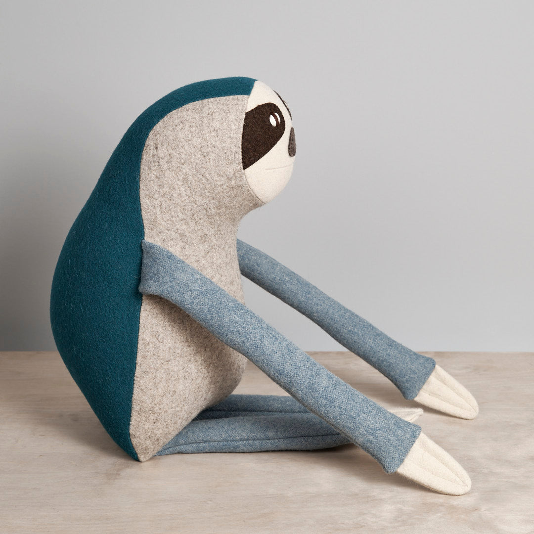 A NED, the Brown-Throated Sloth stuffed animal sitting on a table by Carapau.