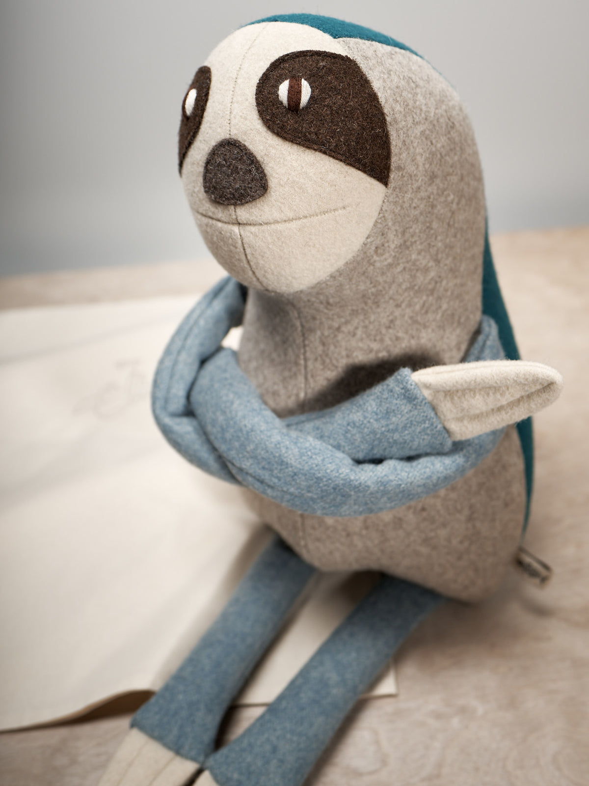 A NED, the Brown-Throated Sloth stuffed animal is sitting on top of a piece of paper.