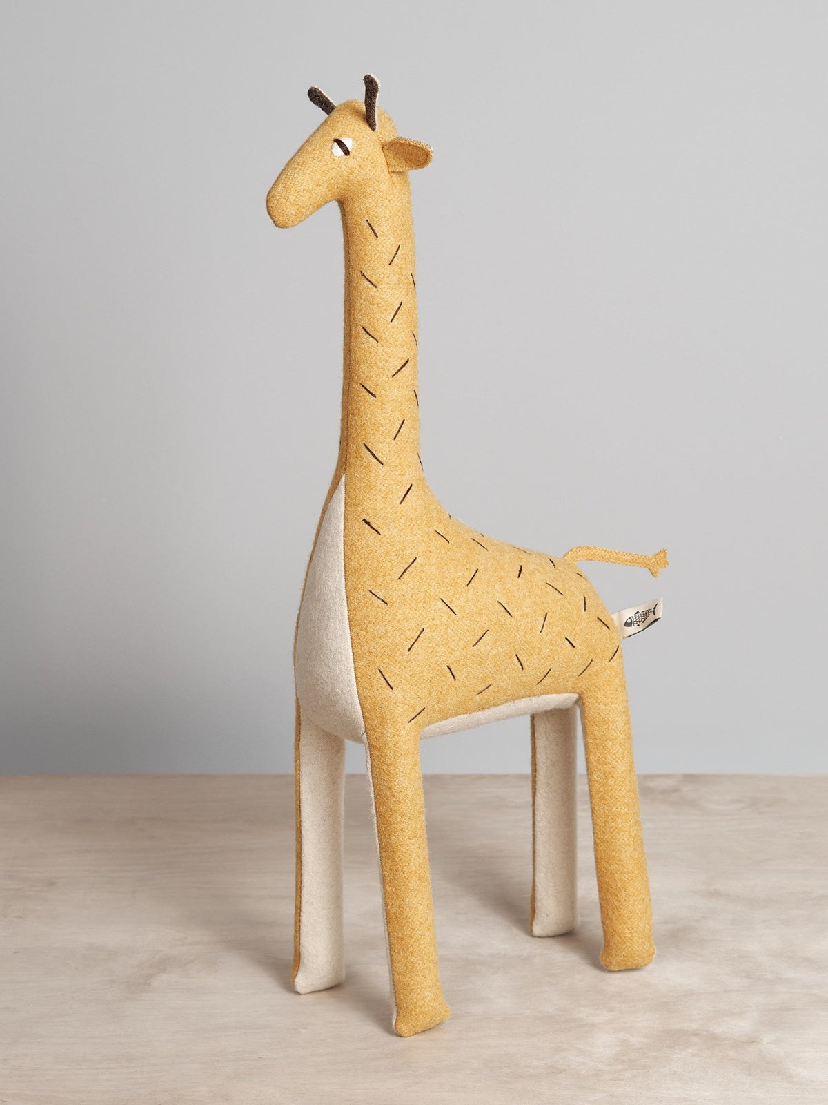 A ZIFFA, the Nubian giraffe, toy standing on a Carapau wooden surface.