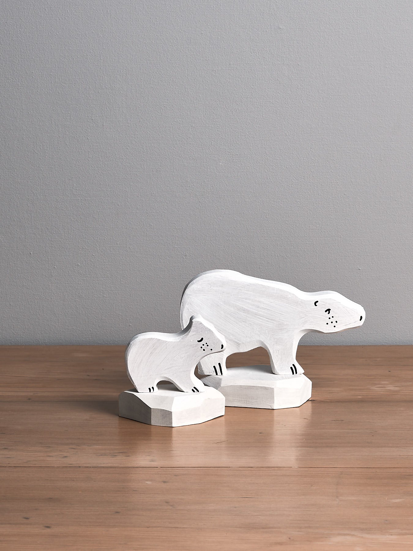 Two wooden Dean's Workshop polar bear figurines on a wooden table.