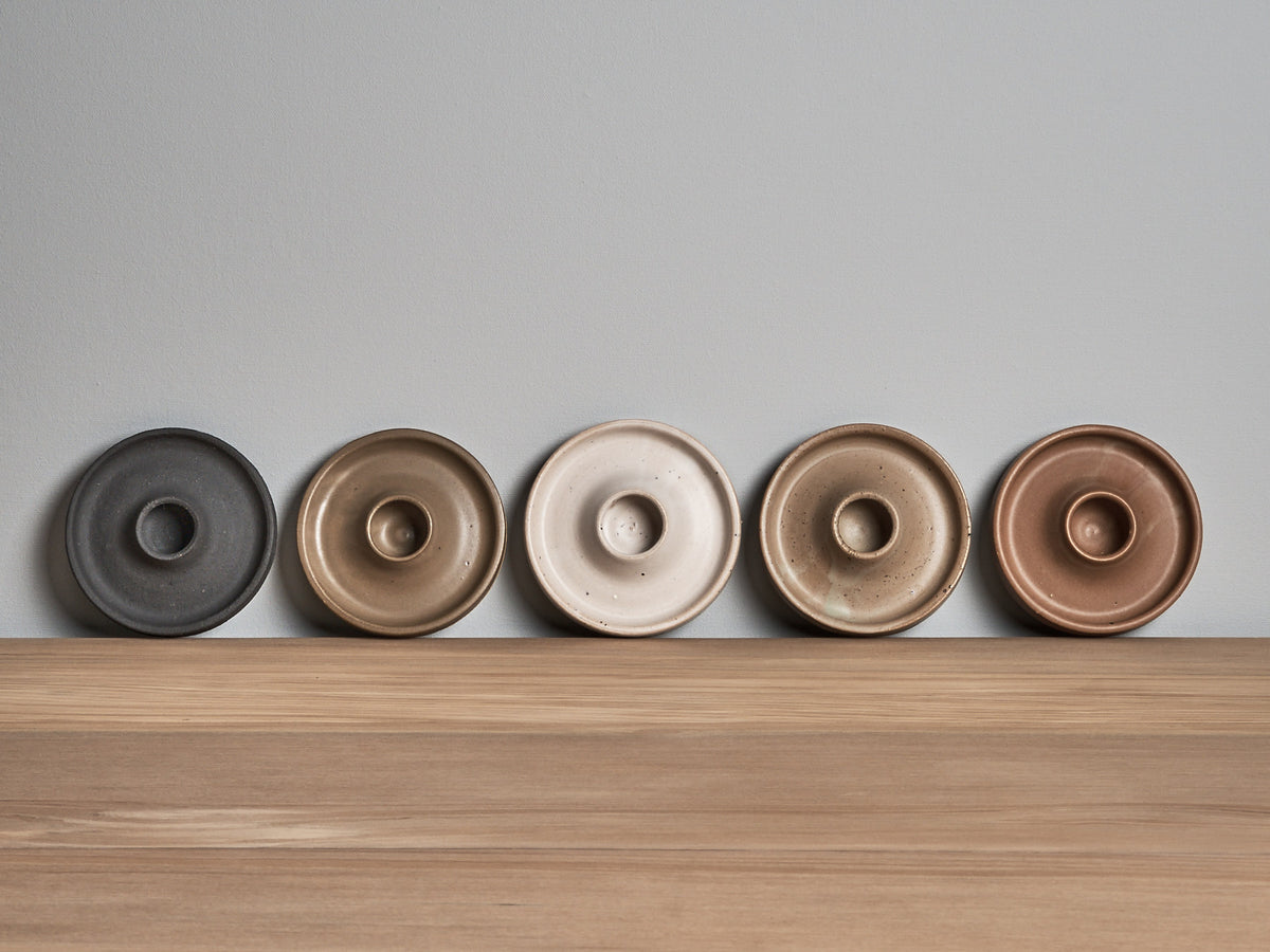 Five Candle Holder – Ochre bowls are lined up on a wooden table.