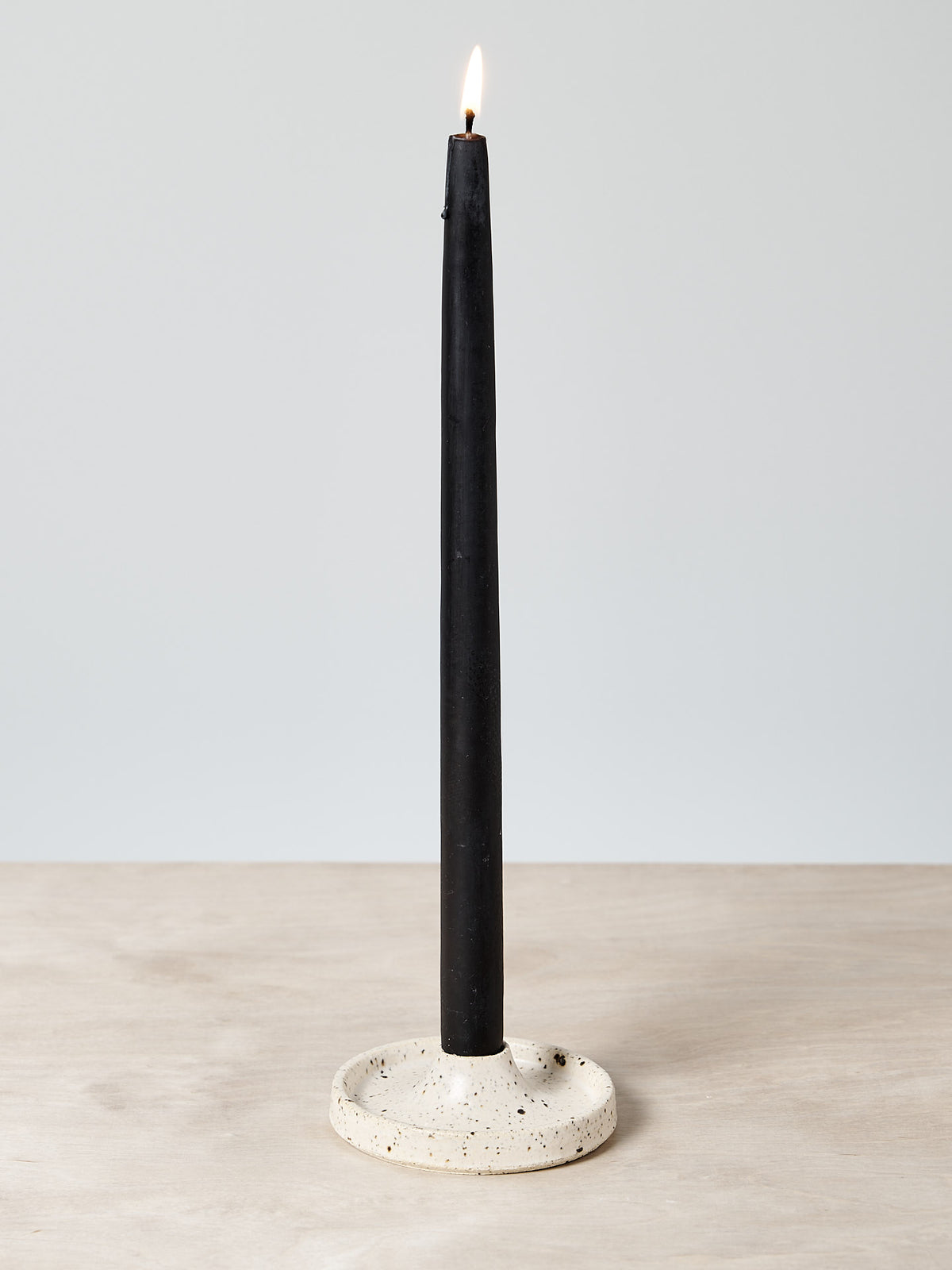 A Candle Holder – Toi Toi is sitting on a wooden table.