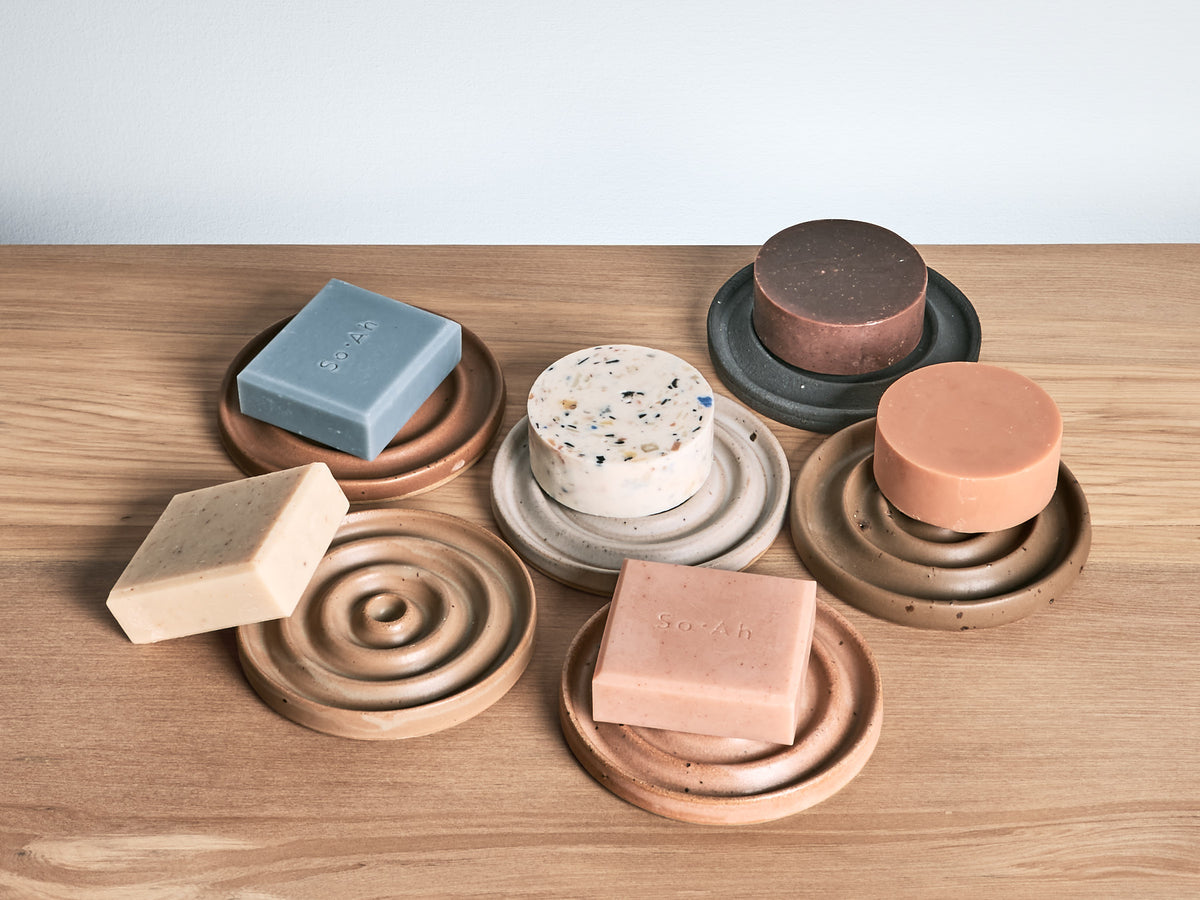 A set of Soap Dish – Ochre bars on a wooden table by deborah sweeney.