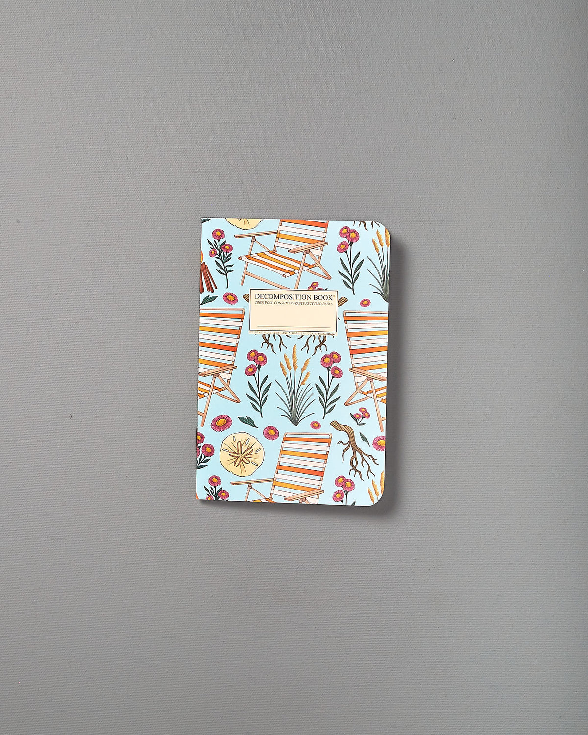 A blue and white Decomposition notebook with a flower on it.