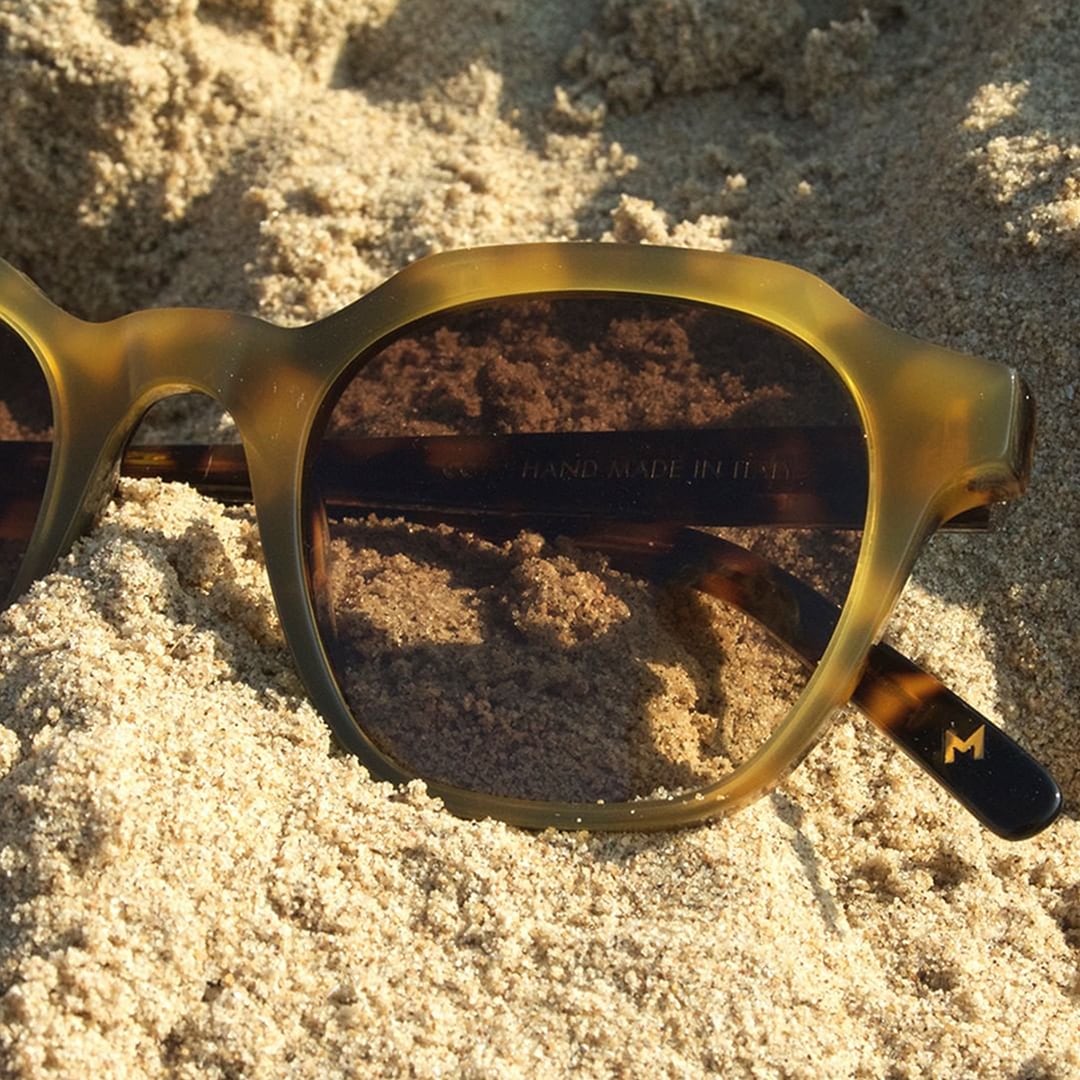 A pair of Dick Moby Barcelona Sunglasses – Pale Rose laying in the sand.