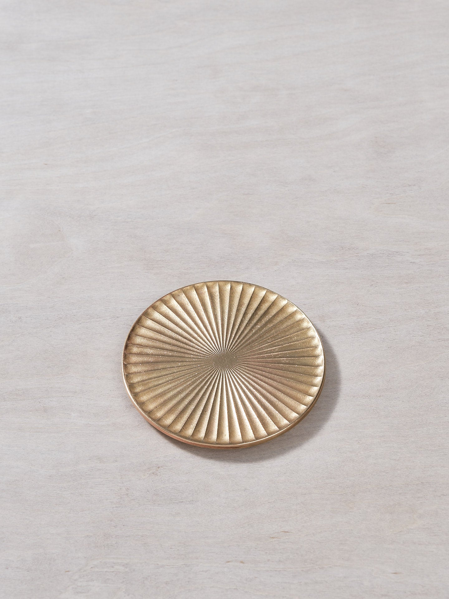A Futagami Kobo Coaster - Solid Brass plate on a wooden surface.