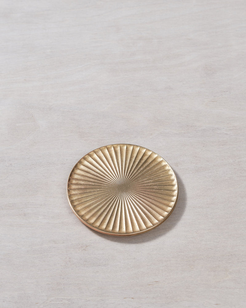 A Futagami Kobo Coaster - Solid Brass plate on a wooden surface.