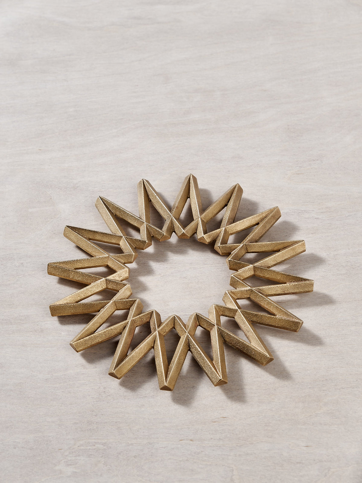 A Galaxy Trivet - Solid Brass bracelet by Futagami on a wooden surface.