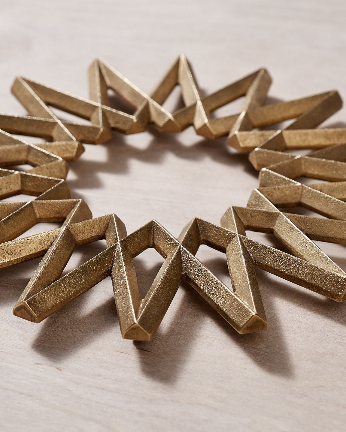 A Galaxy Trivet - Solid Brass bracelet by Futagami on a wooden surface.