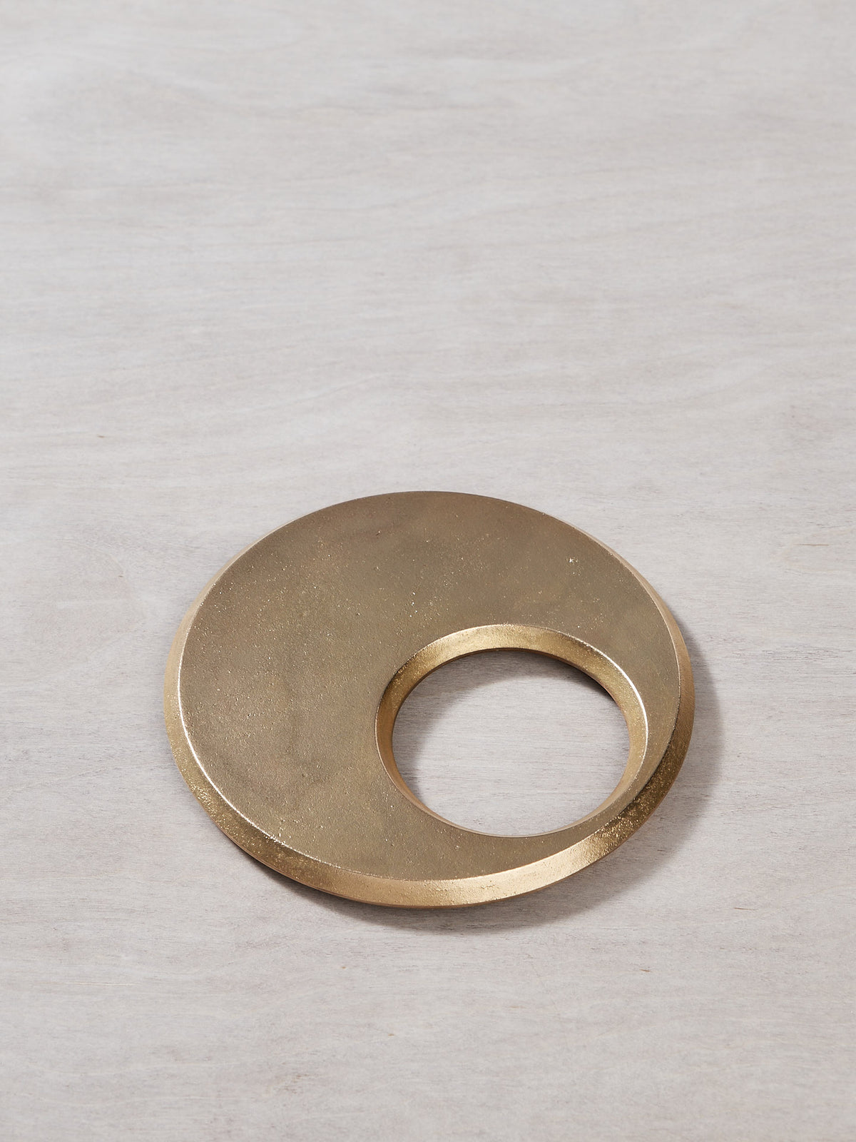 A Moon Trivet – Solid Brass by Futagami on a wooden surface.
