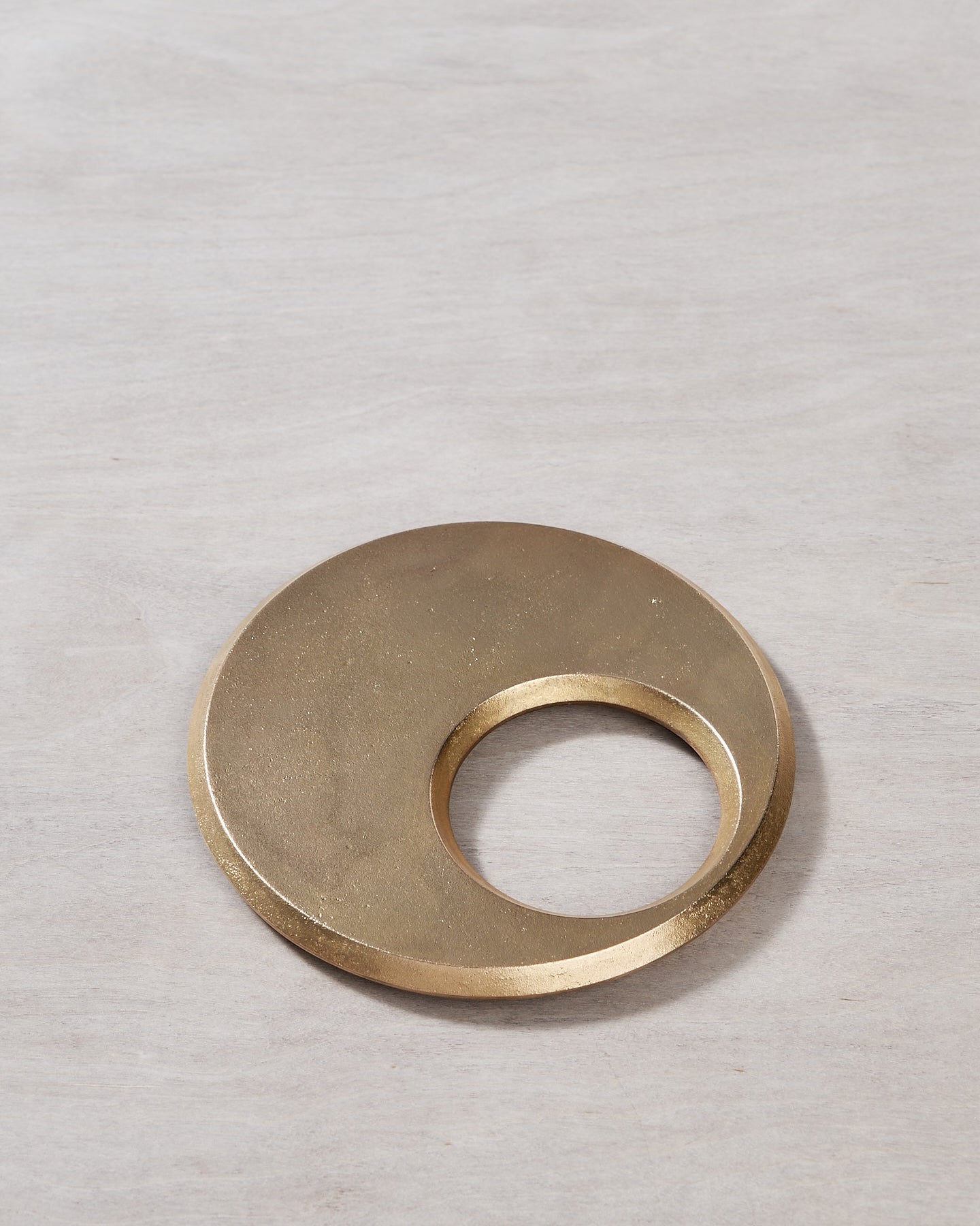 A Moon Trivet – Solid Brass by Futagami on a wooden surface.