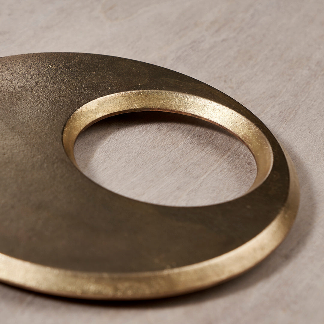 A Moon Trivet – Solid Brass on a wooden surface by Futagami.