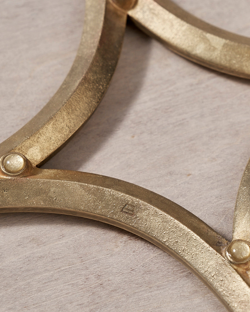 A Star Trivet – Solid Brass by Futagami on a wooden surface.