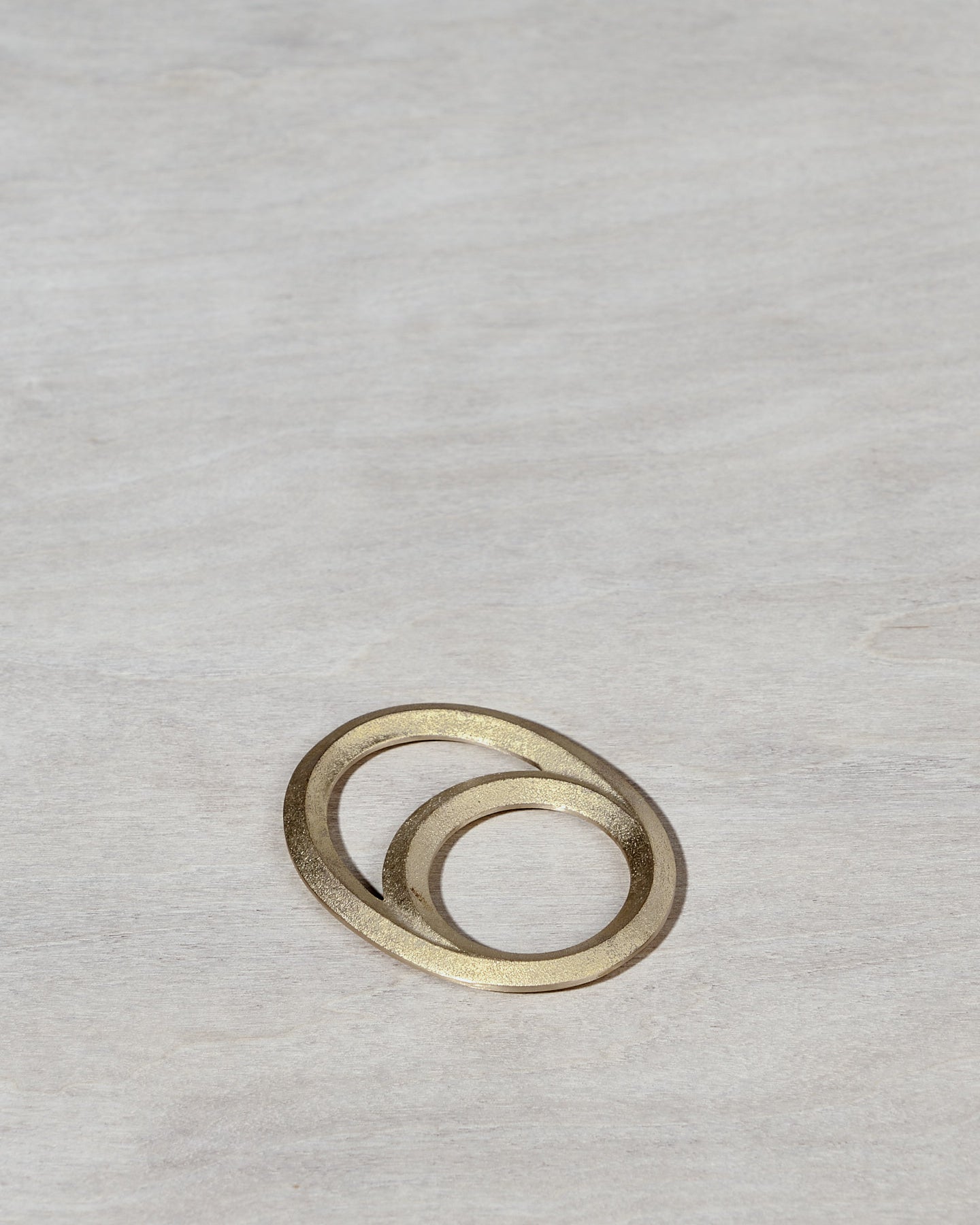 An Eclipse Bottle Opener - Solid Brass by Futagami on a wooden surface.