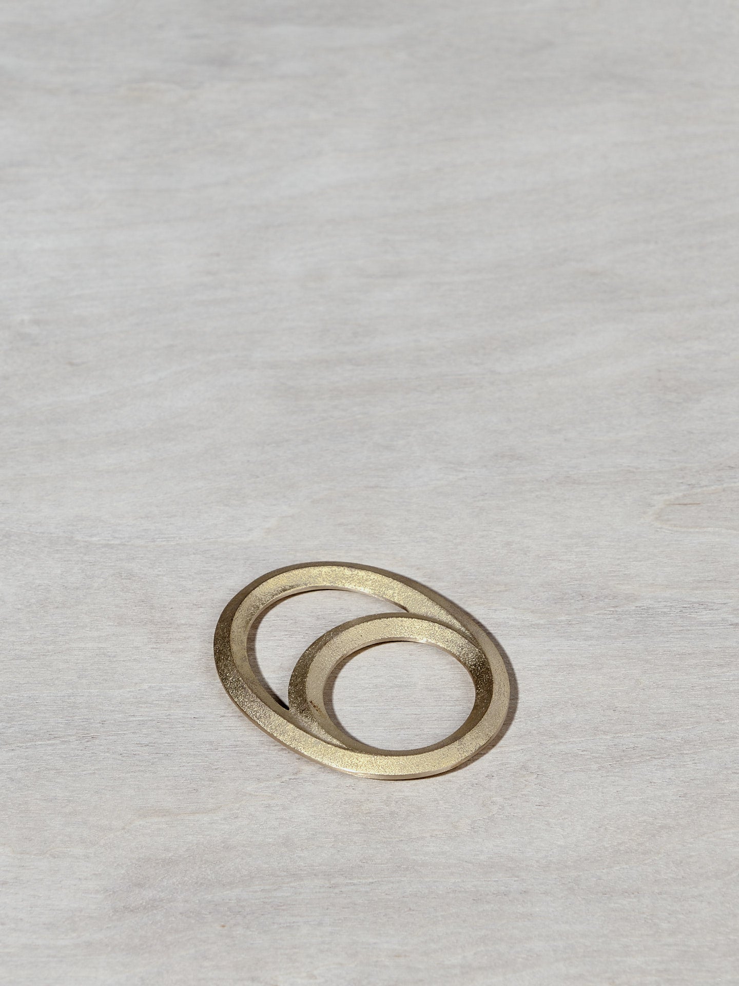 An Eclipse Bottle Opener - Solid Brass by Futagami on a wooden surface.