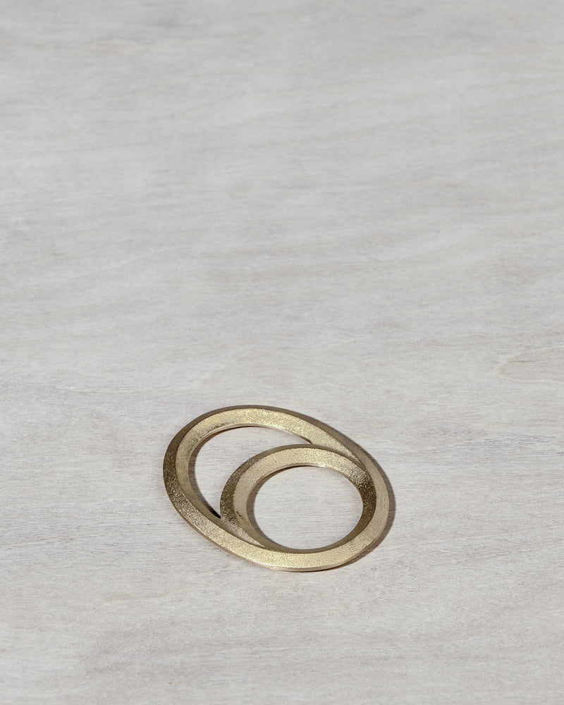 An Eclipse Bottle Opener - Solid Brass by Futagami on a wooden surface.