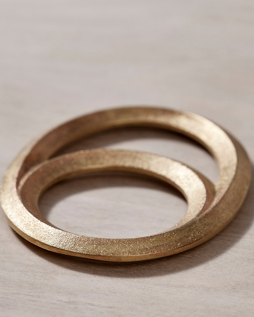 An Eclipse Bottle Opener - Solid Brass by Futagami on a wooden surface.